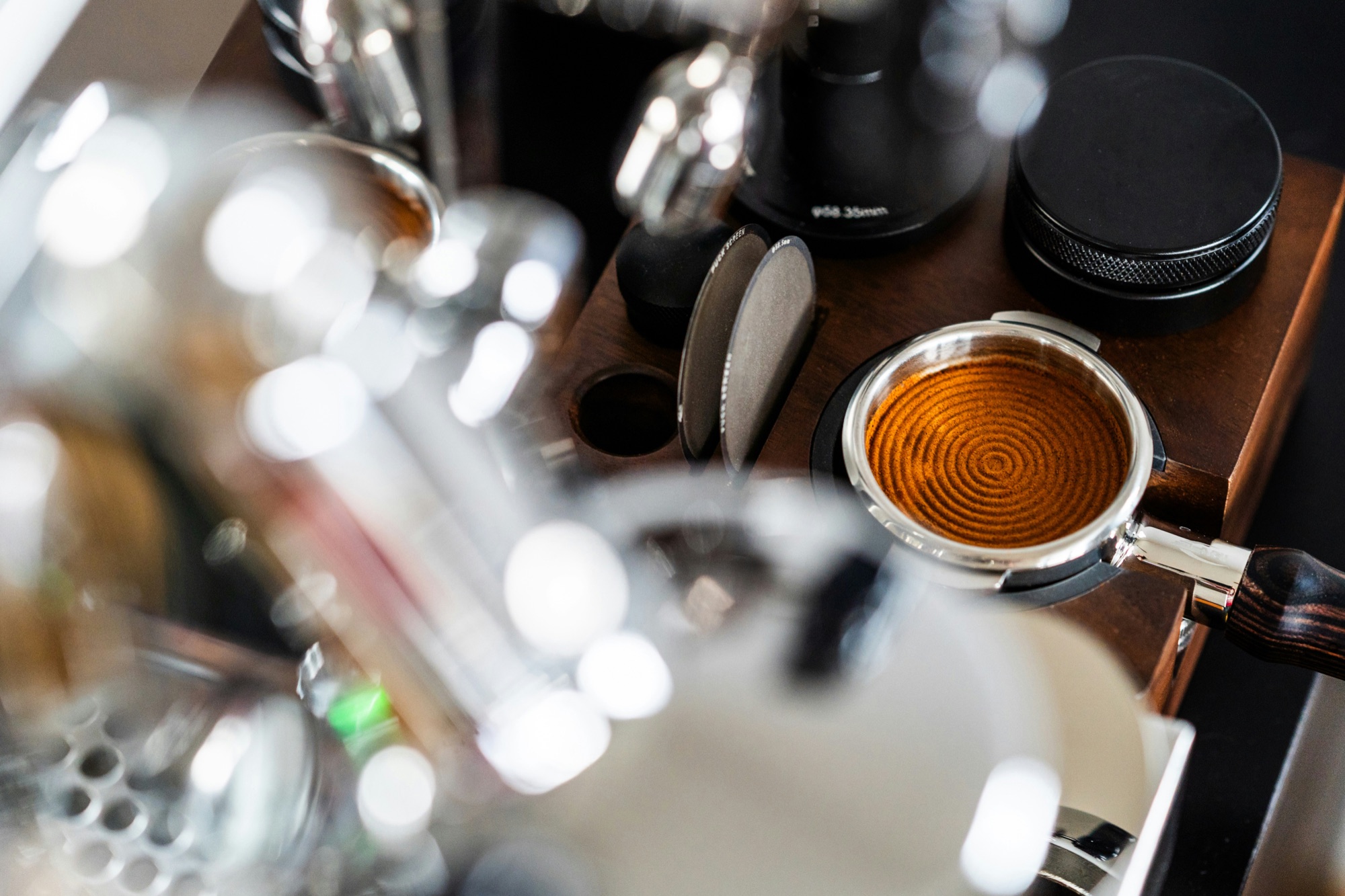 A level, evenly distributed espresso puck in a portafilter beside a tamper